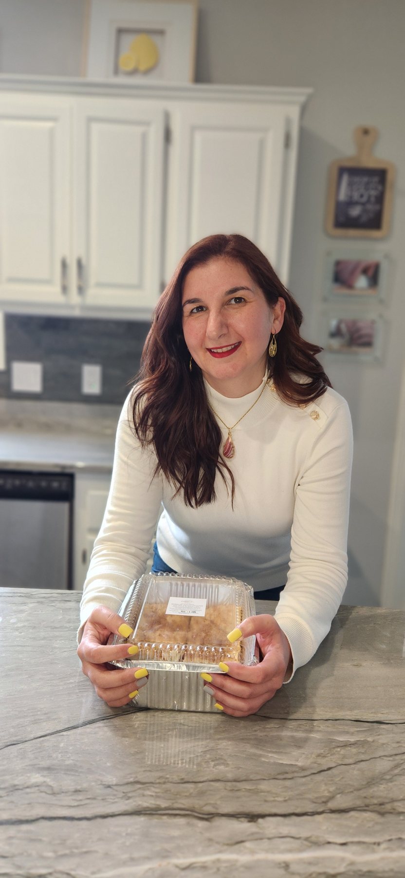 Sarah holding a box of CLEObetcha baklava in her kitchen