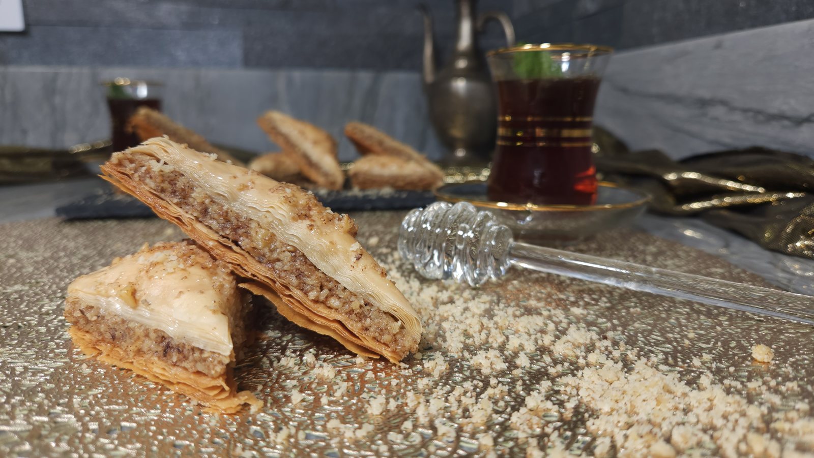 Close-up of baklava showing flaky phyllo layers, walnut filling, and a honey dipper
